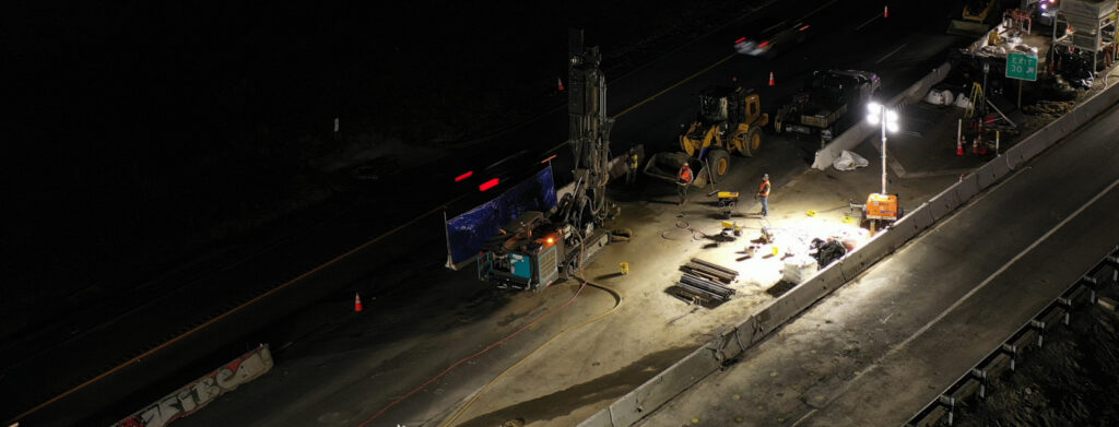 Nighttime ground improvement drilling operation on active roadway construction site