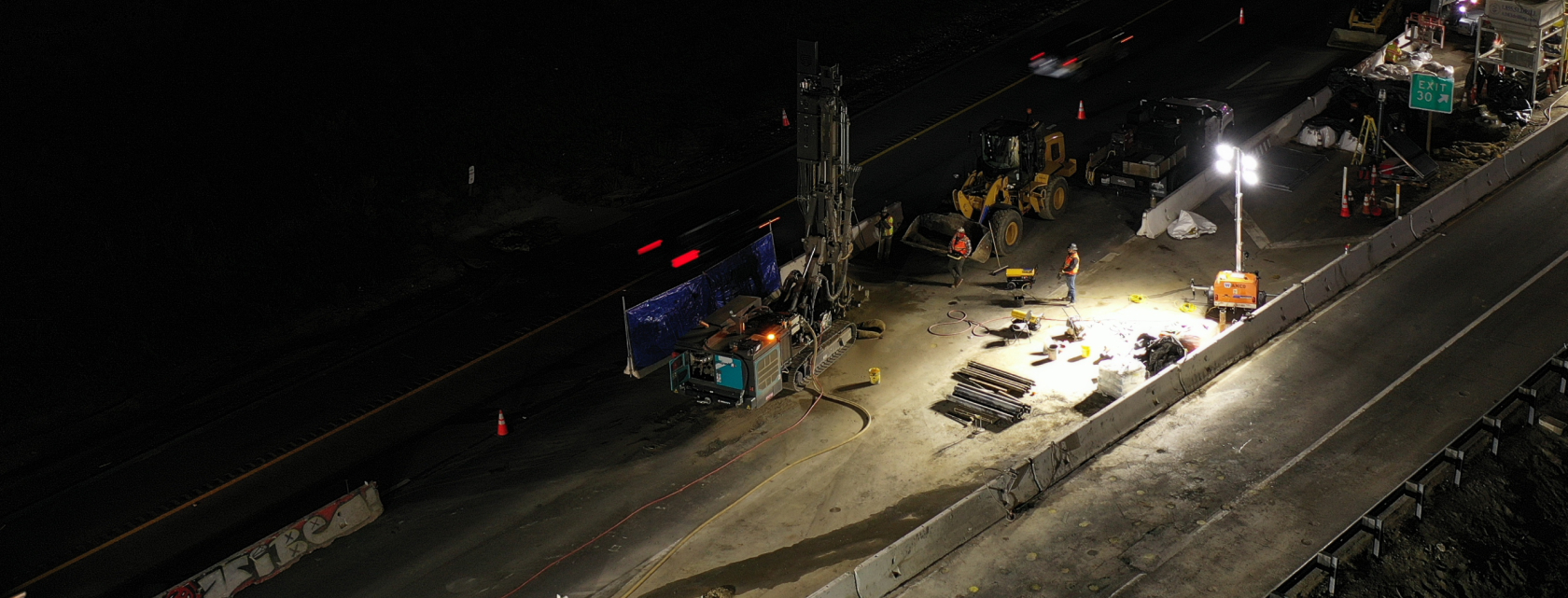 Nighttime ground improvement drilling operation on active roadway construction site