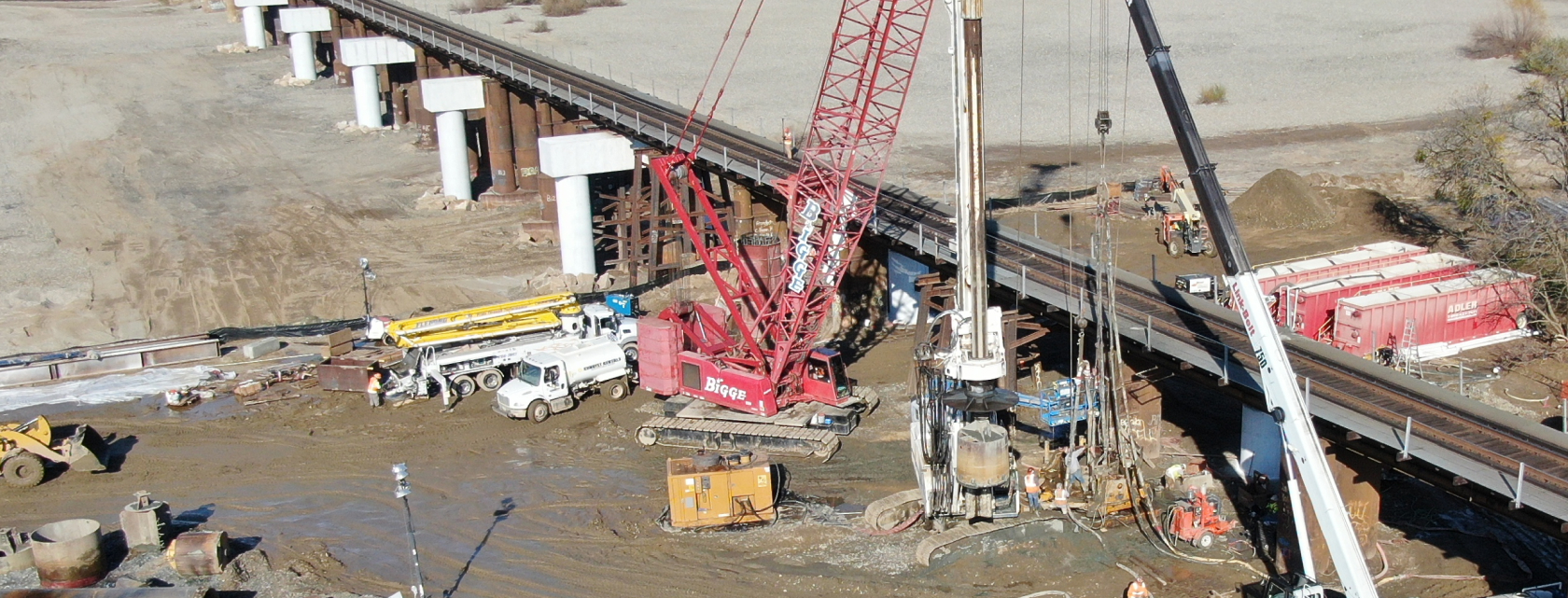 Public infrastructure bridge foundation work with cranes and drilling equipment