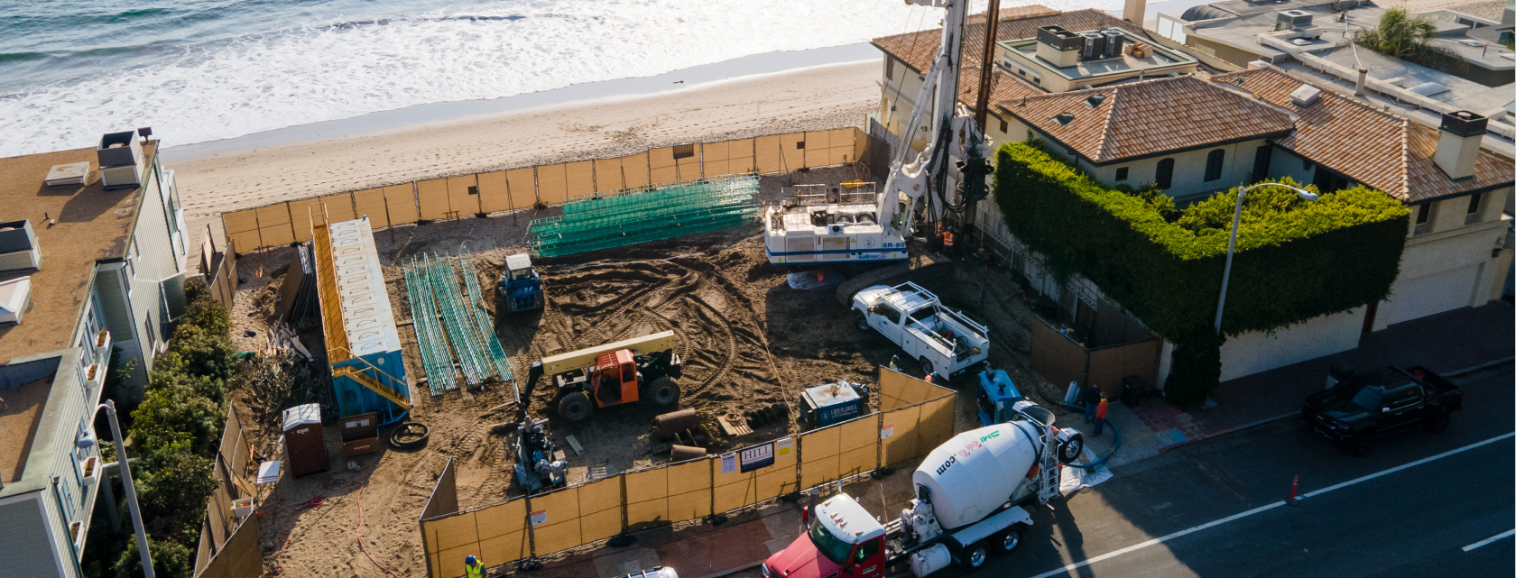 Residential and mixed-use construction site with drilling equipment near coastal development