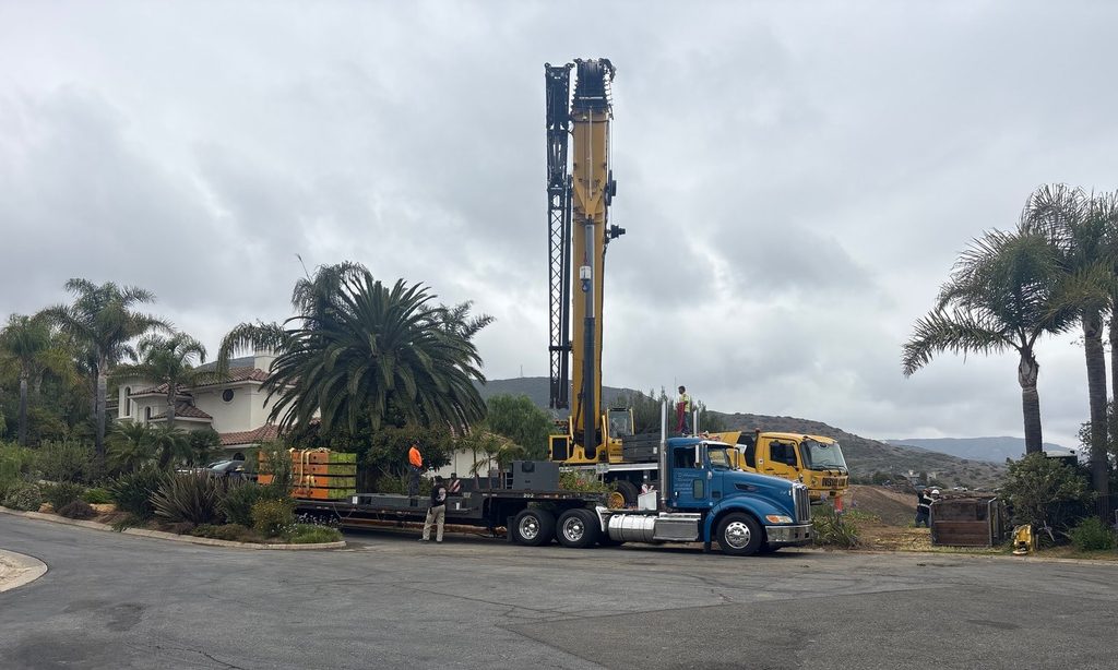 Drilling equipment arriving at the paved staging area above the slope.